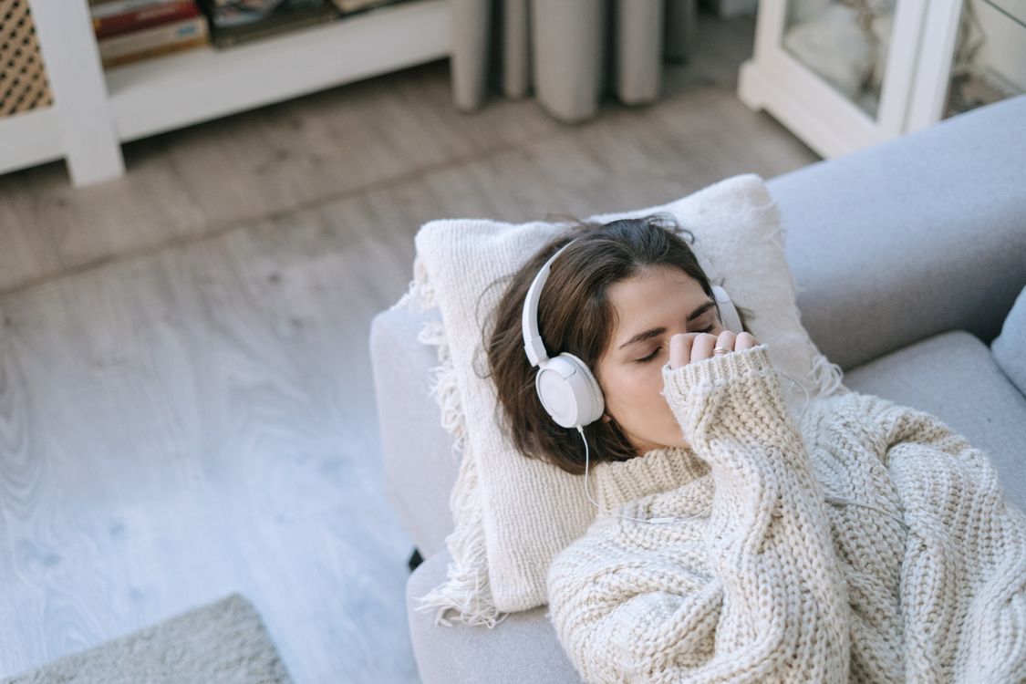 A Woman wearing Headphone Lying on the Couch · Free Stock Photo
