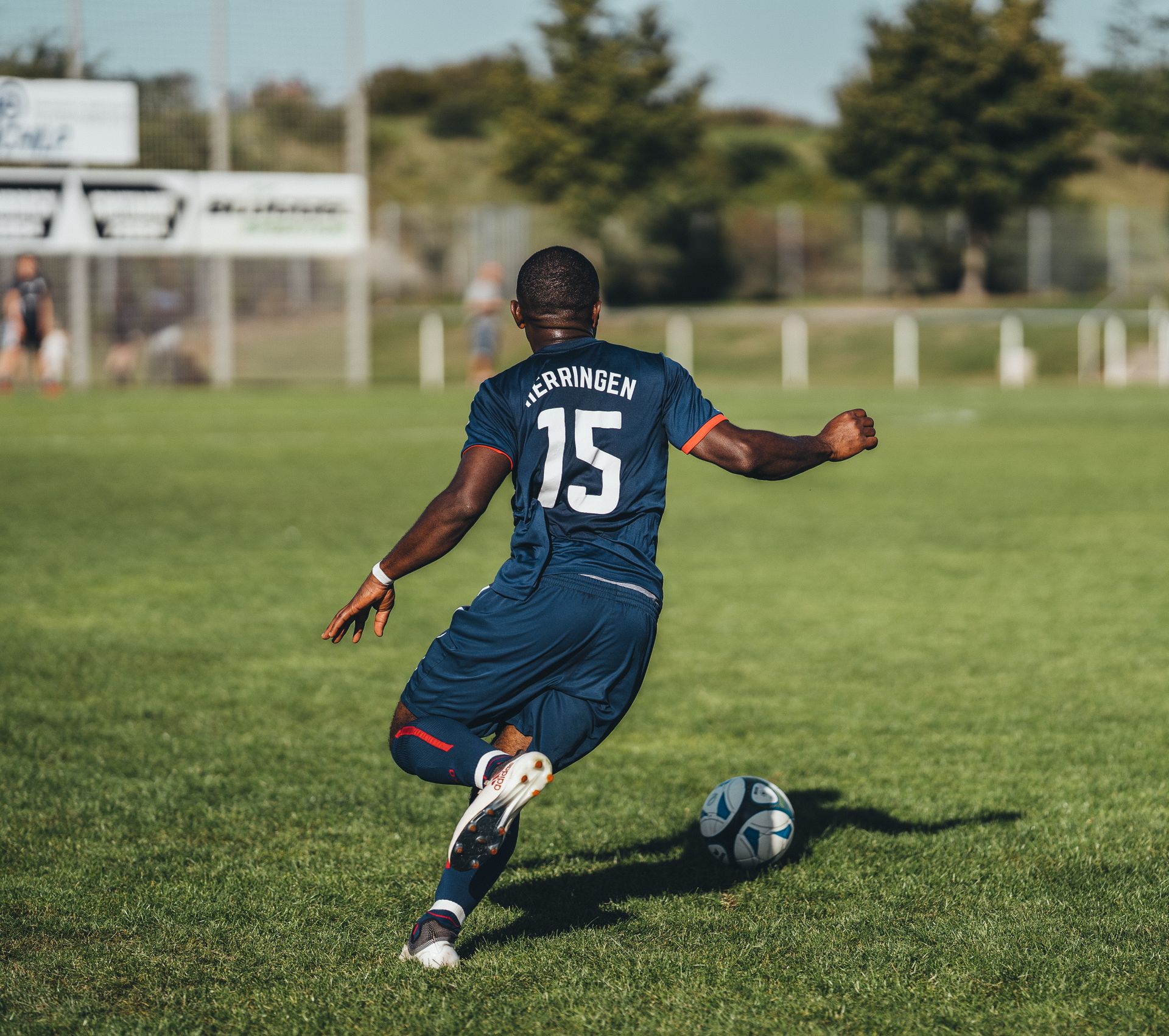 Young African football player kicking a soccer ball on the pitch