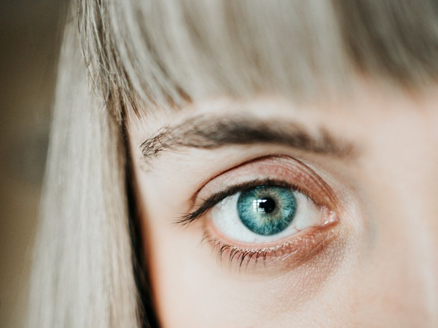 A macro shot of a blue human eye highlighting the detailed iris and eyelashes.