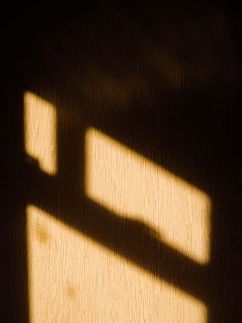 Free Sunlit window shadow casting a geometric pattern on a dark wall. Stock Photo
