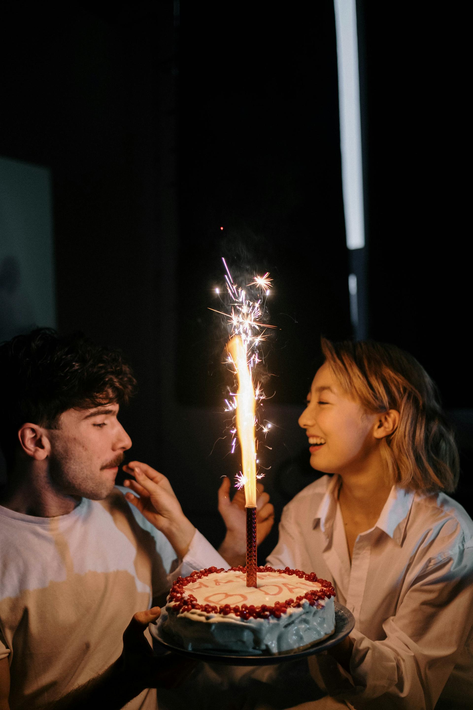 Couple celebrating birthday with cake and sparkler