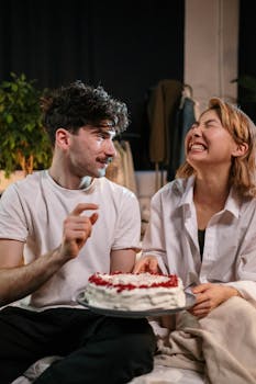 Happy couple enjoying a birthday celebration with cake at home.