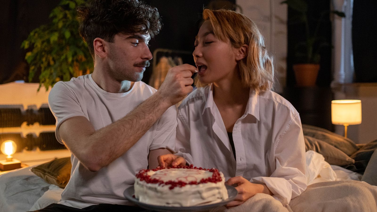 Two adults sharing cake while sitting together indoors