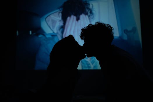Silhouette of a couple sharing a romantic kiss with a projected background. Captures intimacy and love.