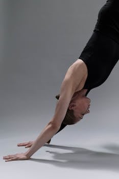 A woman in athletic wear performing a downward dog yoga pose in a studio.