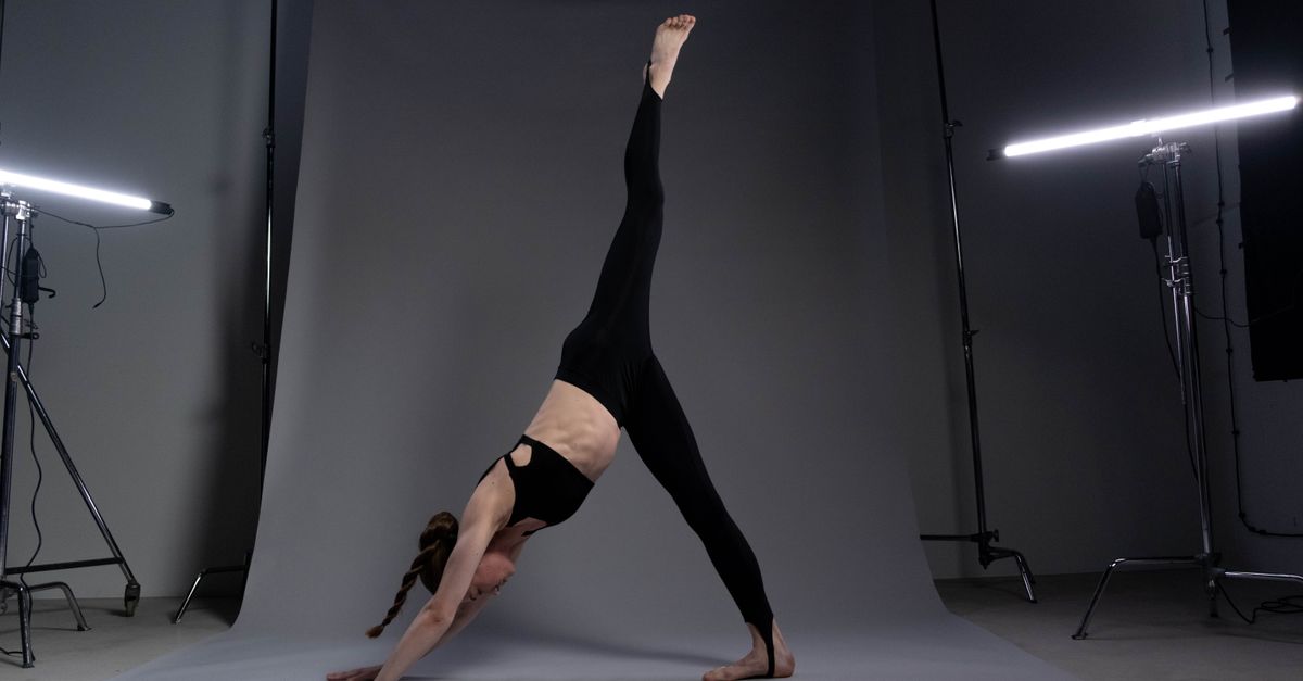 A serene hot yoga studio with a person in a deep stretch, sweat dripping, soft lighting