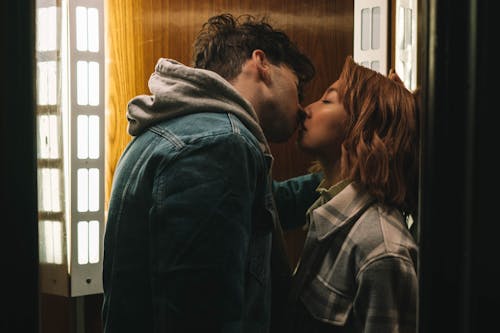 Free Man and Woman Kissing Near the Window Stock Photo