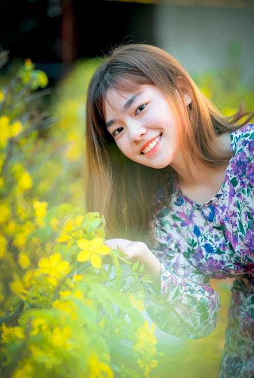 Pretty Woman in Floral Dress Holding Yellow Flowers