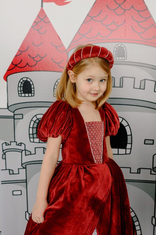 Free Child Wearing a Red Gown Beside a Castle Wall Painting Stock Photo