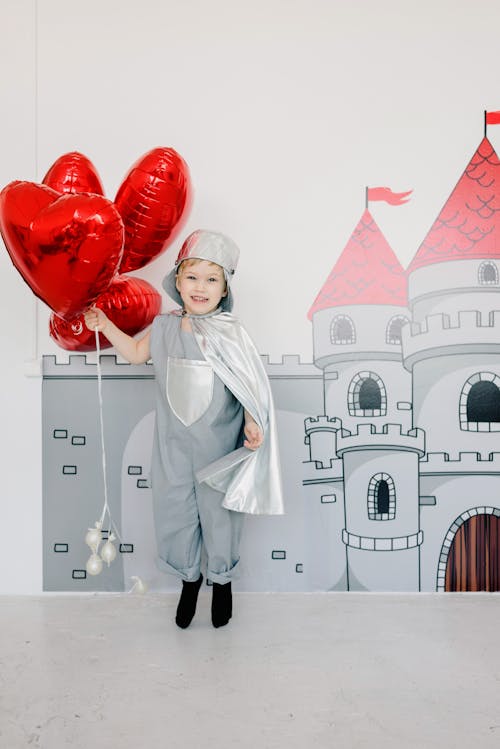 Free Kid Wearing a Costume Holding Red Balloons Stock Photo