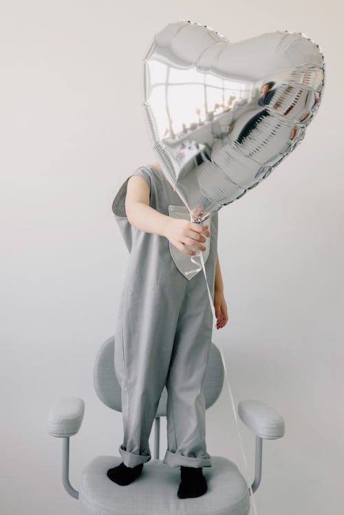 Child Standing on a Chair Holding a Balloon