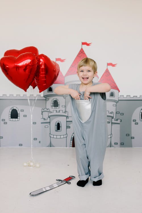 Child Wearing a Costume Standing Near the Balloons