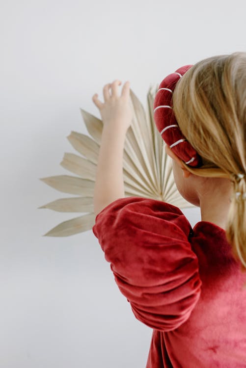 Girl in Red Dress Touching Palm Leaf