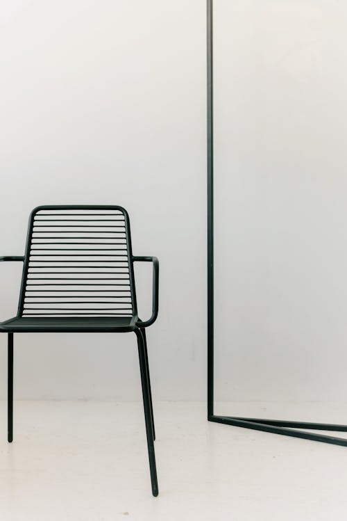 A Black Chair Near the Metal Frame on a White Surface