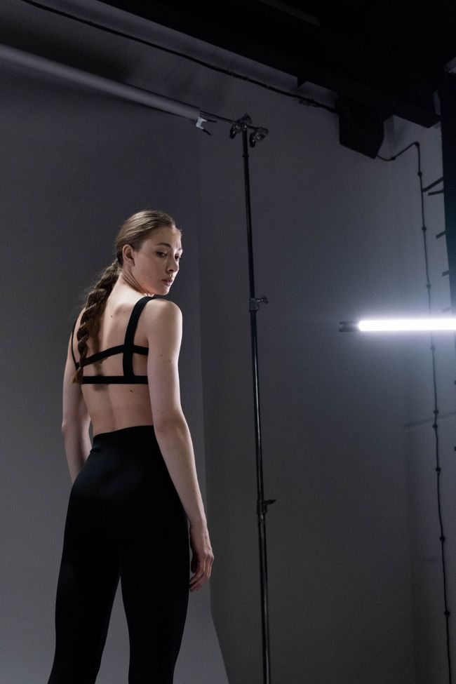Model in a black bra and ribbed legging on a studio set — photo by cottonbro studio on Pexels