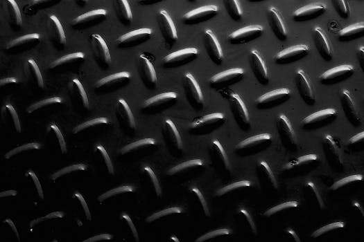 Seamless black tread plate metal texture with geometric patterns and industrial design elements.