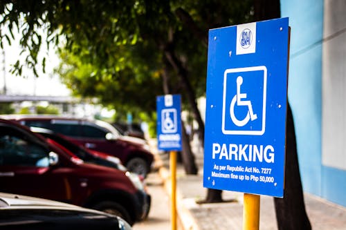 Signboard representing rule for disabled people parking only near vehicles and sidewalk in city