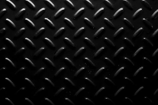 Full frame background of seamless geometric abstraction made of oval shaped bulges on black surface