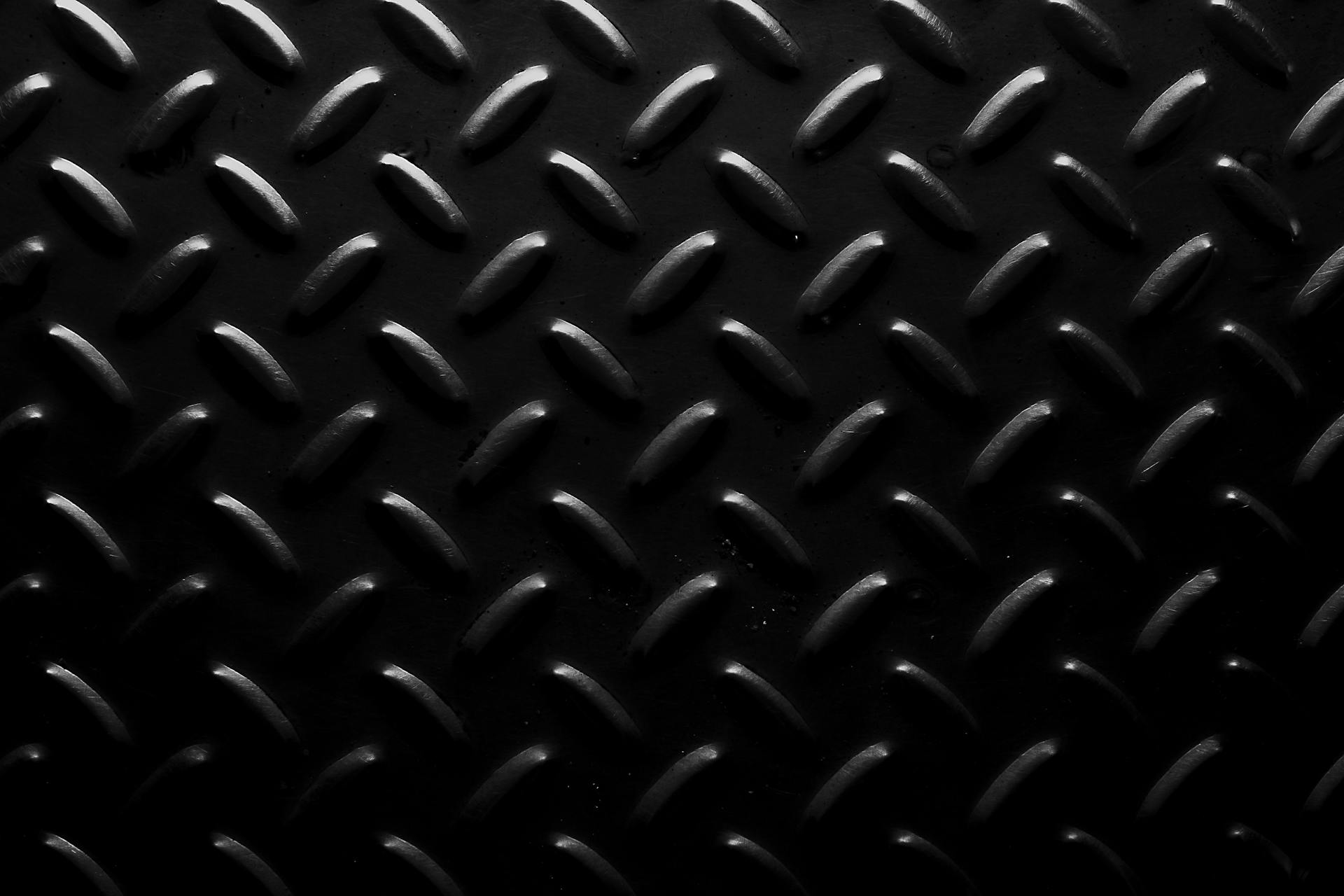 Full frame background of seamless geometric abstraction made of oval shaped bulges on black surface