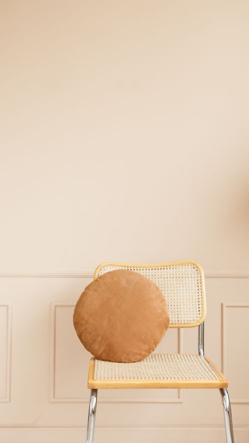 Free A modern minimalist wicker chair paired with a round throw pillow against a neutral background, perfect for design inspiration. Stock Photo