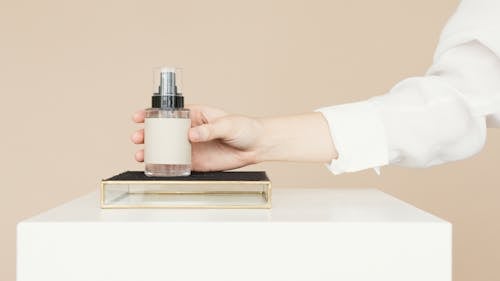Free Person Holding White and Silver Bottle Stock Photo