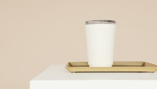 bardak, bej renkli arka plan, beyaz masa içeren Ücretsiz stok fotoğraf