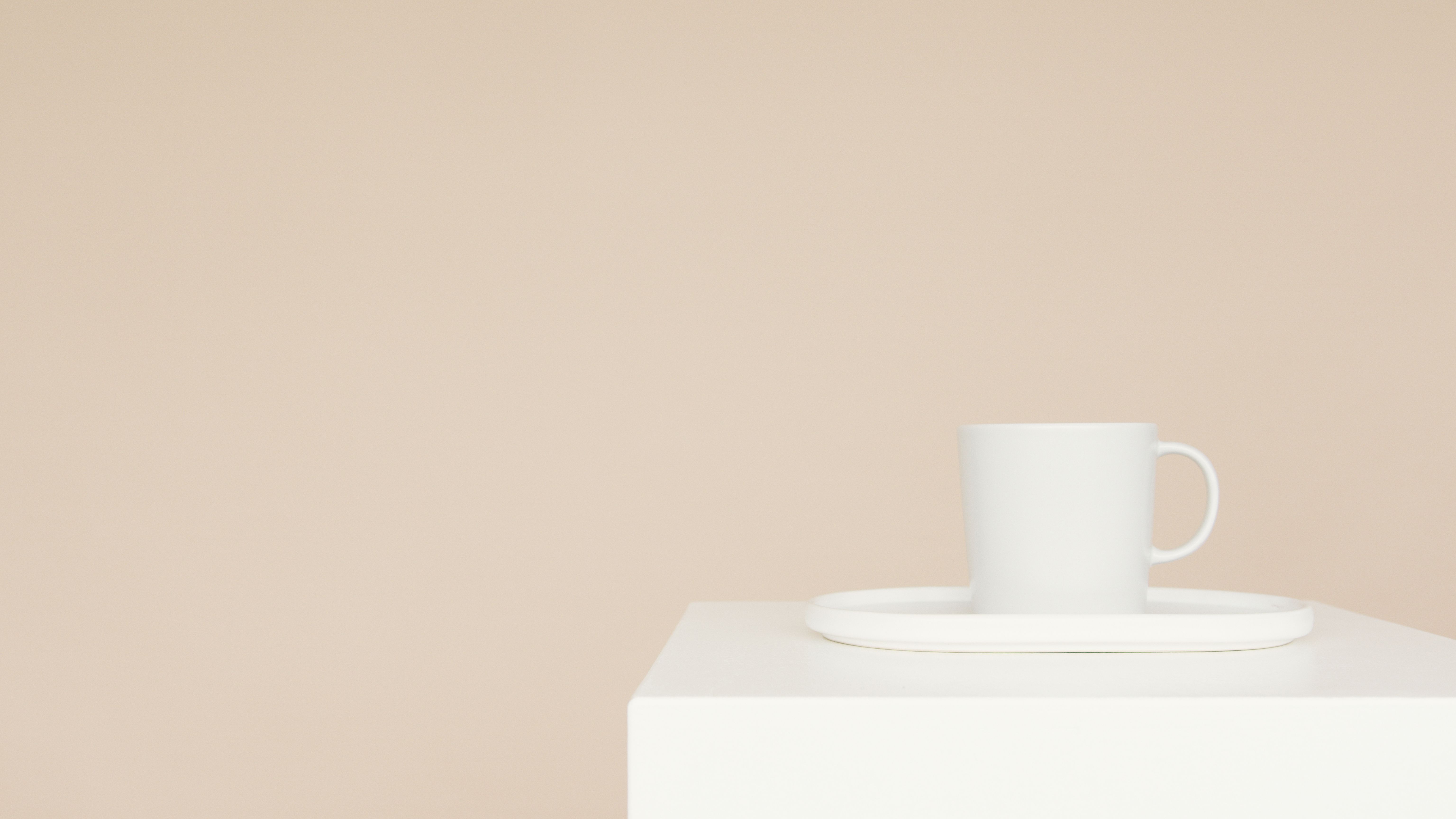 A white mug on a tray on a minimalist white block with a beige background, perfect for modern decor.