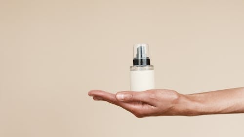 Person Holding White and Silver Bottle