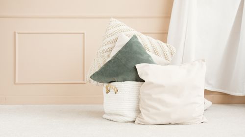 Free A stylish collection of textured cushions against a beige wall, showcasing minimalist elegance. Stock Photo