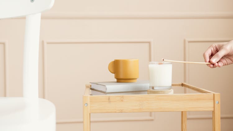 A Person Lighting A Scented Candle On A Side Table