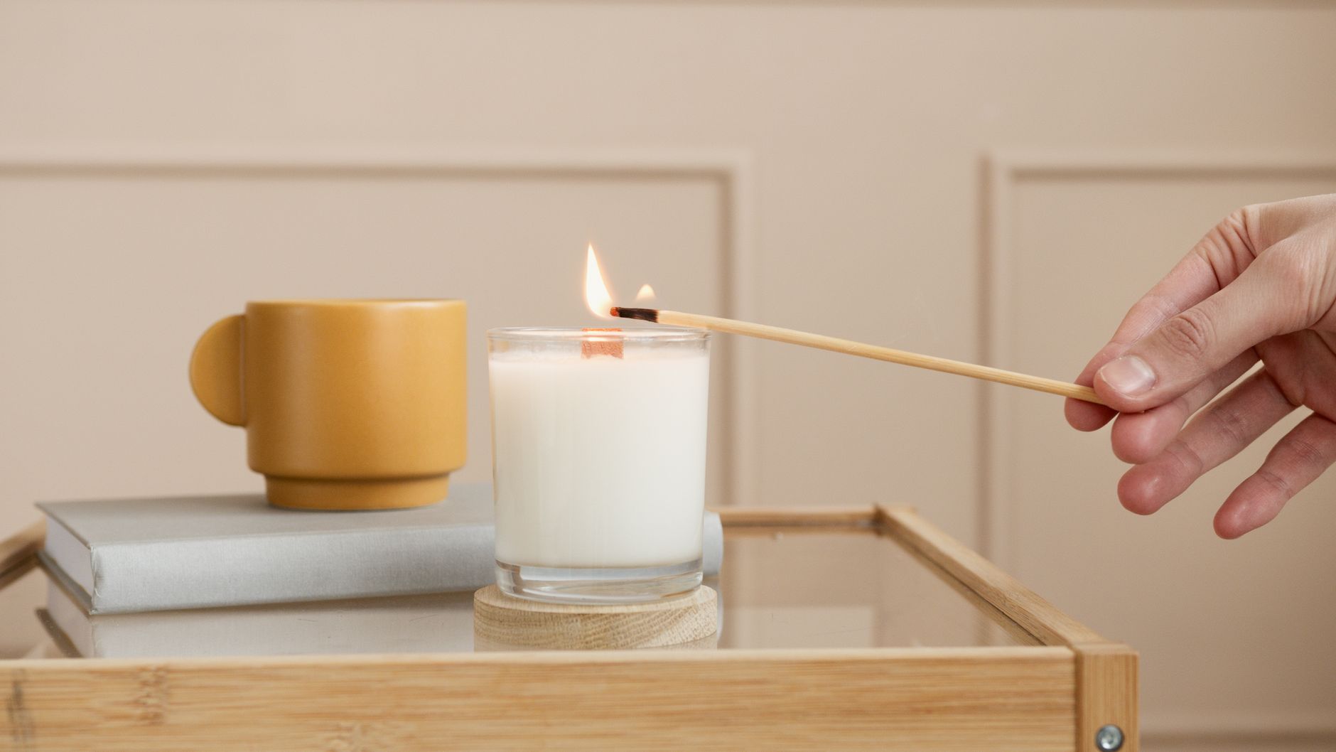 A serene interior setting with a lit aromatic candle and mustard mug on a glass table.