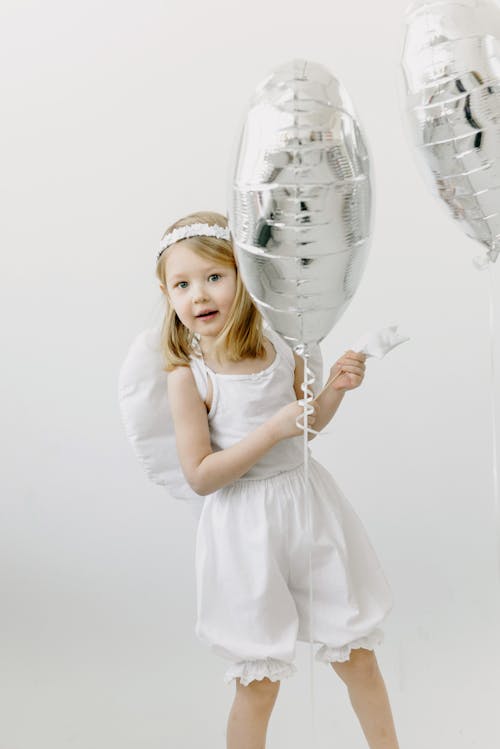 An Adorable Girl Holding Heart Shaped Silver Balloons