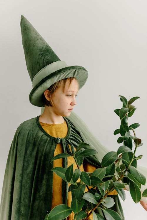 Young Girl Wearing a Hat Standing Beside a Plant