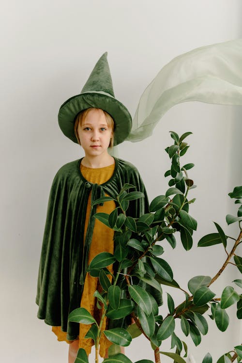Pretty Girl Wearing a Green Costume Standing Beside a Plant