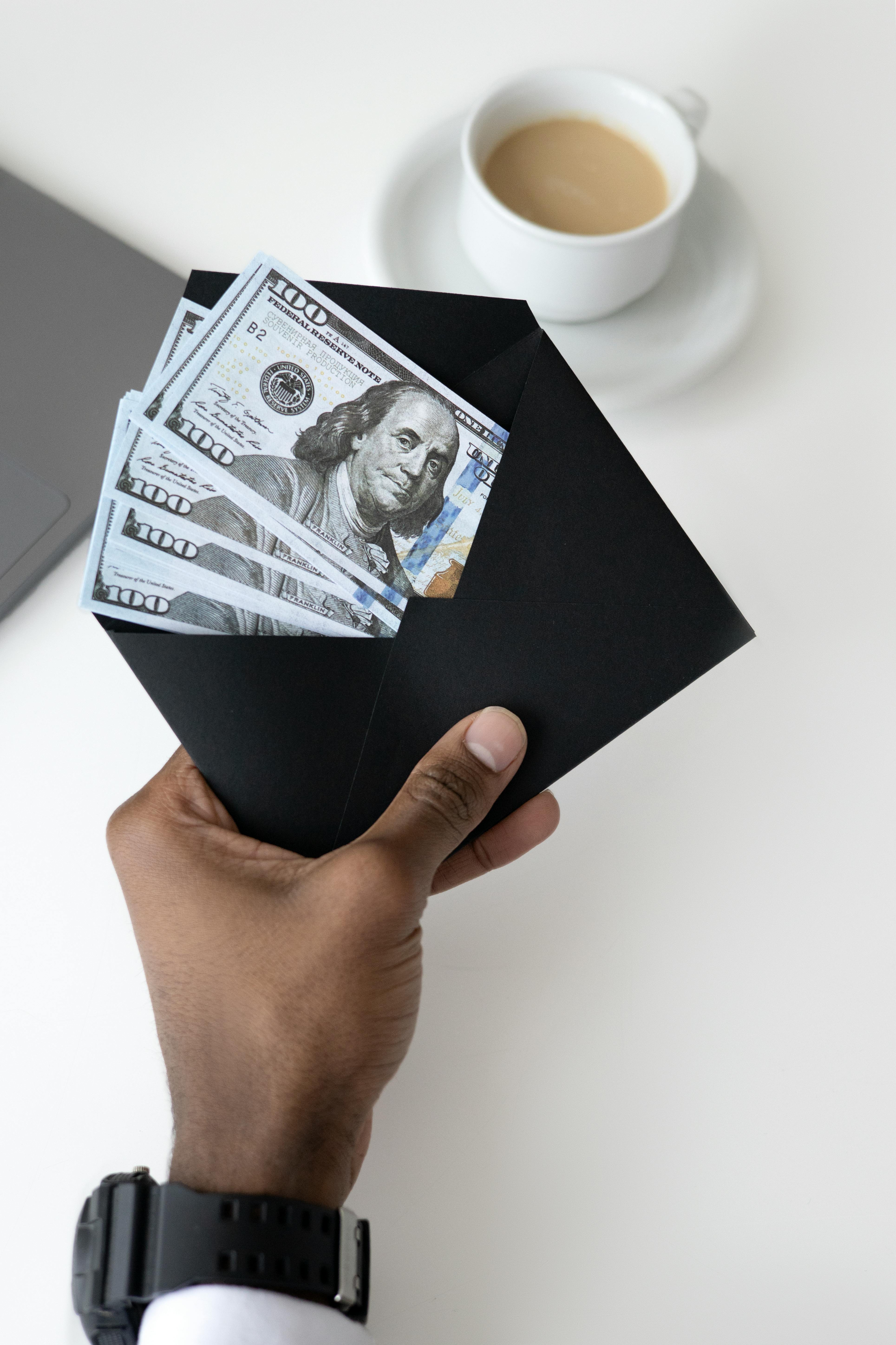 photo of person holding black enevelope with money bills