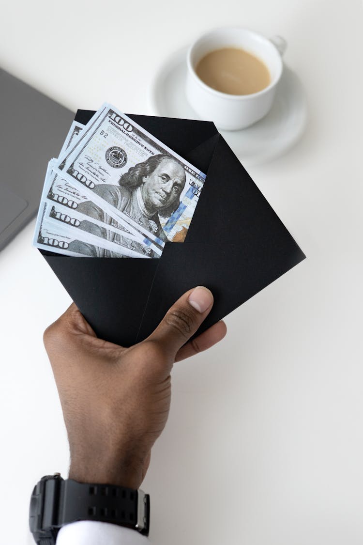 Photo Of Person Holding Black Enevelope With Money BIlls