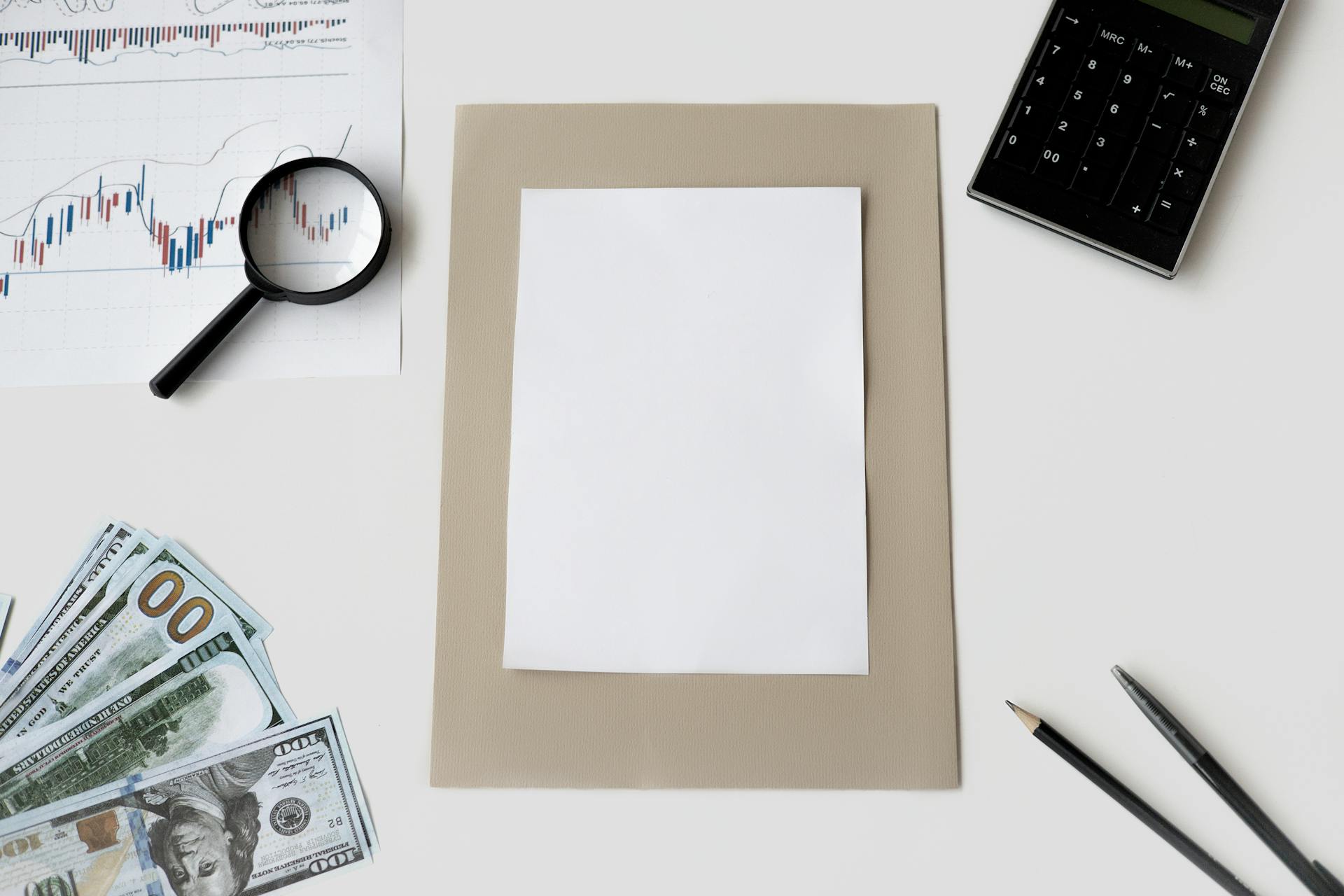 Flat lay of financial tools and blank paper for planning or mockup.