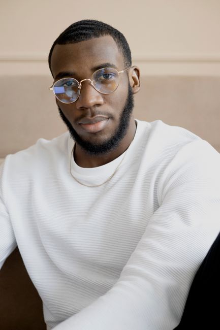 Portrait of a stylish man with glasses in a white sweater, exuding confidence.