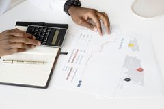 Overhead view of a person analyzing financial documents using a calculator for investment planning.