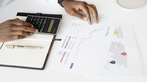 Overhead view of a person analyzing financial documents using a calculator for investment planning.