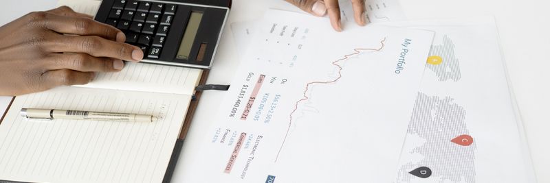 Overhead view of a person analyzing financial documents using a calculator for investment planning.