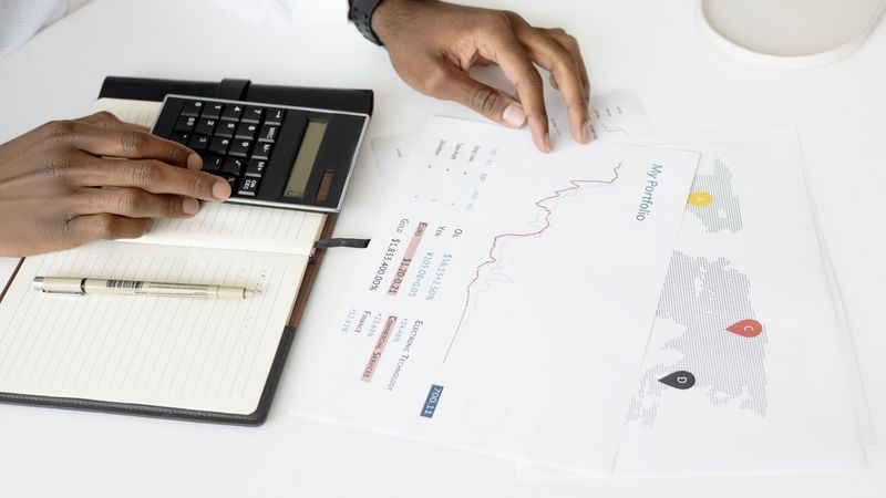 Overhead view of a person analyzing financial documents using a calculator for investment planning.