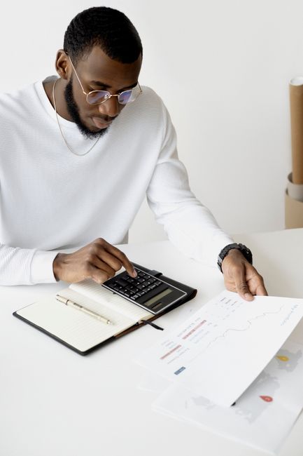 Professional analyzing documents and using a calculator at an office desk. Professional analyzing documents and using a calculator at an office desk.