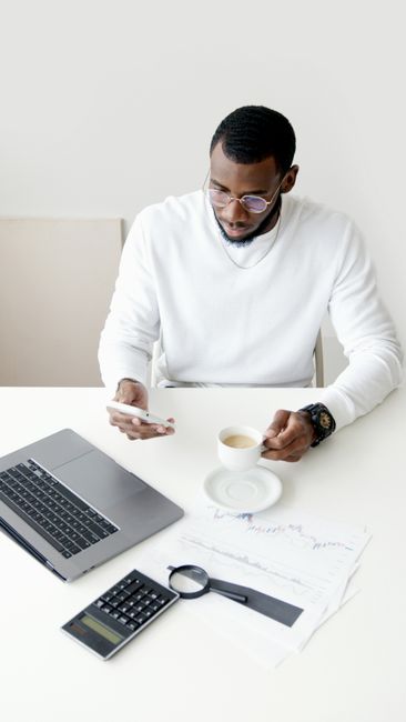 A professional man multitasking with a smartphone and coffee in an office setting. A professional man multitasking with a smartphone and coffee in an office setting.