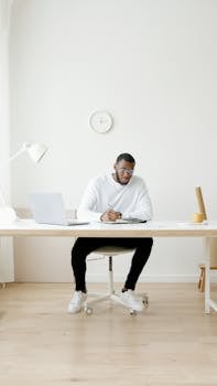 A professional working diligently at a modern desk in a minimalist office setting.