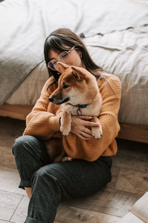 Free A Woman in Brown Sweater Hugging Her Dog Stock Photo