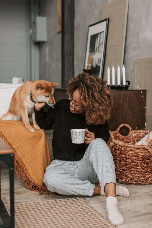 Free A Woman Sitting on the Floor while Holding Her Dog Stock Photo