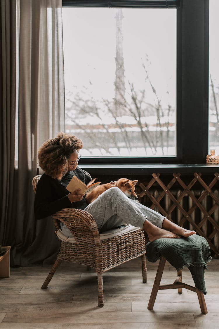 A Woman Reading A Book While Sitting On A Chair