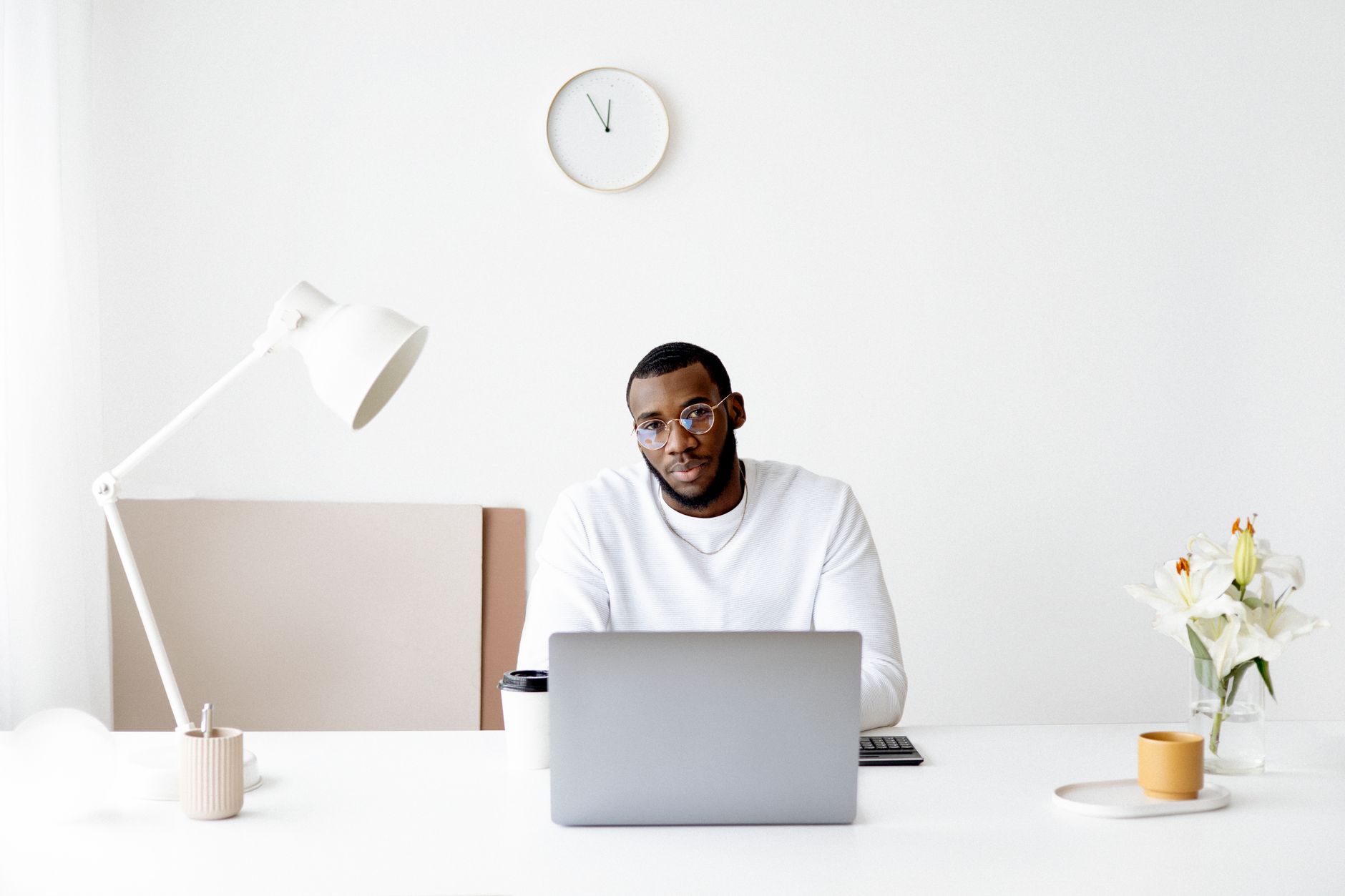 Stylish businessman working at a laptop in a bright, modern office setting with minimalistic design.