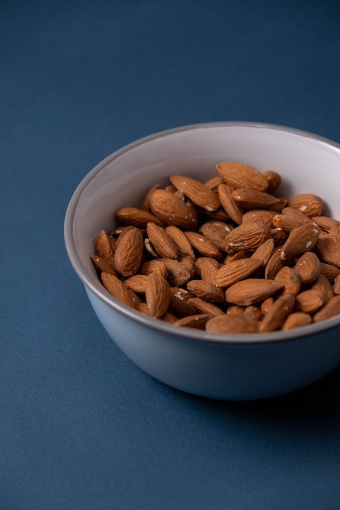 Almonds in a bowl on a blue background